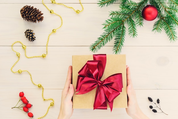 Cadeau avec un ruban rouge dans les mains pour Noël et Nouvel An sur un fond en bois