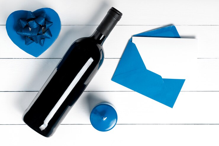 Cadeau, vin, lettre, bougie sur une surface en bois blanche.