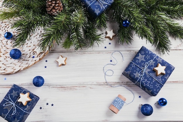 Cadeaux, branches de sapin, décorations bleues sur bois