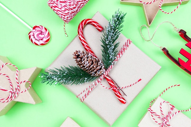 Cadeaux d'emballage écologique de Noël sur vert, concept de vacances de Noël écologique, surface d'hiver festive de décoration écologique. Cadeau avec bonbons et sapin, boîtes en papier et jouet d'arbre en bois