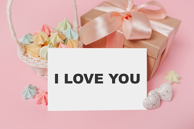 Cadeaux avec lettre de note sur fond rose isolé avec des bonbons, l'amour et la Saint-Valentin concept avec texte je t'aime