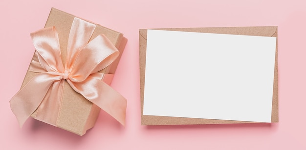 Cadeaux avec lettre de note sur une surface rose isolée
