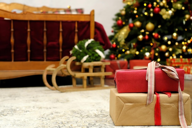 Les cadeaux de Noël attachés avec un ruban se trouvent sur le sol dans le contexte d'un arbre de Noël