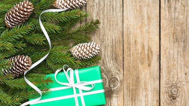 Cadeaux de Noël avec des branches de sapin sur une table en planches.