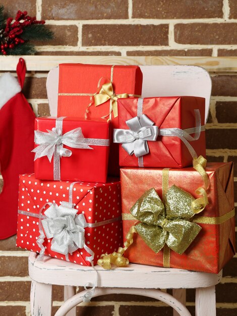 Cadeaux de Noël sur chaise sur fond de mur de briques brunes