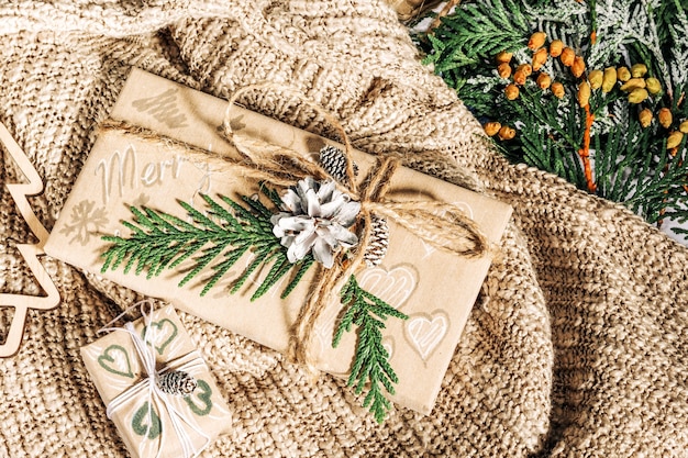 Cadeaux de Noël avec coffret décoré de pommes de pin et de brindilles sur un tissu en coton