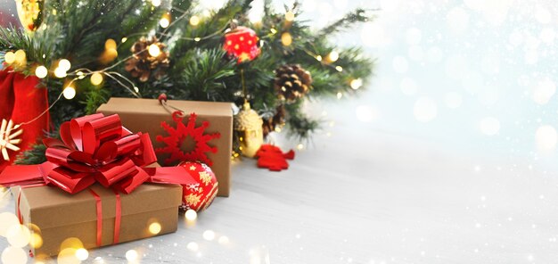 Cadeaux de Noël dans des boîtes et des sacs d'artisanat sur fond de branches de Noël et de lumières rougeoyantes. Carte de voeux ou bannière à vendre. Bonne année. Espace de copie