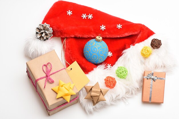 Cadeaux de Noël du père Noël. Vue de dessus de fond blanc de bonnet de Noel. L'atmosphère est une question de détails. Ambiance festive du nouvel an et de noël. Attributs des vacances d'hiver. Bonnet de Noel et coffret cadeau de Noël.