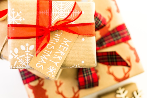 Cadeaux de Noël emballés dans du papier brun avec des rubans rouges.