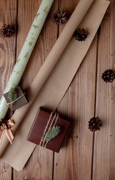 Cadeaux de Noël emballés dans du papier craft sur table en bois. Processus d'emballage des cadeaux. Contexte de style de vie. Vue d'en-haut. Concept de Noël.