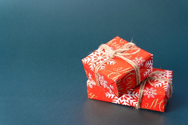 Cadeaux de Noël emballés dans du papier rouge avec de la ficelle sur fond gris-vert avec espace de copie. Vue de côté