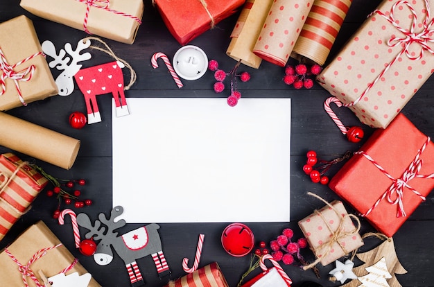 Cadeaux de Noël fabriqués à la main emballés dans du papier kraft, des rouleaux et une décoration de Noël sur fond de bois. Lieu de travail pour la préparation des décorations du nouvel an. Concept de vacances d'hiver.