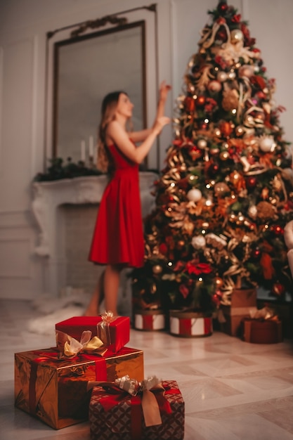 Cadeaux de Noël sur le fond de la femme décorant l'arbre de Noël