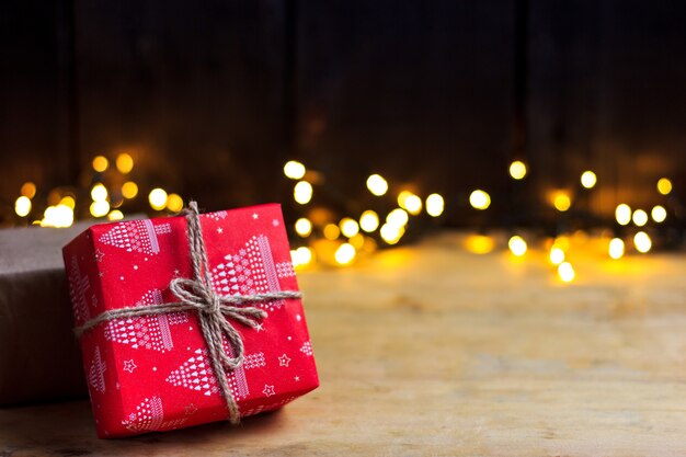 Cadeaux de Noël nouvel an sur une table en bois clair avec des guirlandes lumineuses