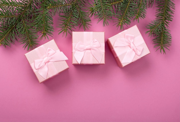 Cadeaux de Noël avec ruban rose sur fond pastel rose avec décorations festives