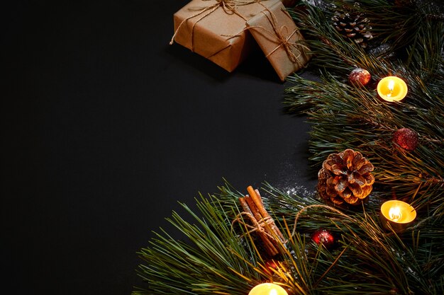 Cadeaux de Noël, sapin de Noël, bougies, décor coloré, étoiles, boules sur fond noir. Vue de dessus. Espace de copie. Nature morte à plat lay Nouvel an