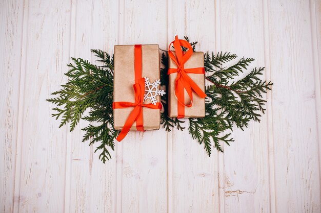 Les cadeaux de Noël se trouvent sur les branches de sapin sur la table en bois