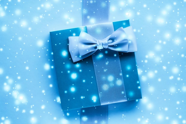 Cadeaux de vacances d'hiver et neige rougeoyante sur fond bleu gelé Cadeaux de Noël surprise