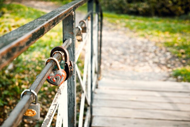 Cadenas d'amour rouillé en forme de coeur accroché sur rail de pont en bois