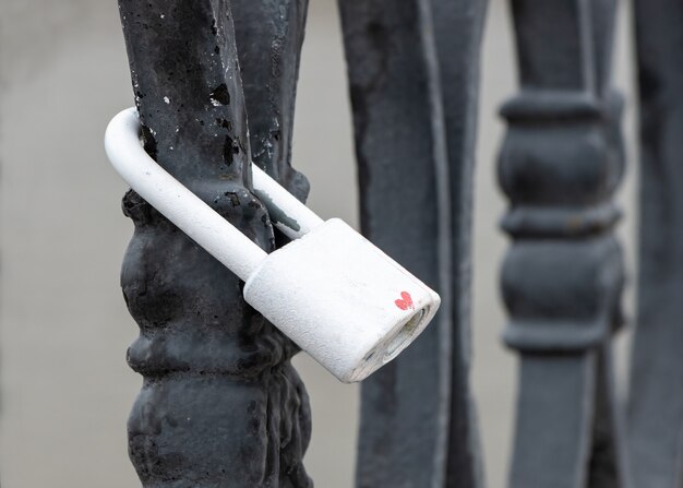 Cadenas blanc verrouillé avec signe d'amour sur clôture métallique