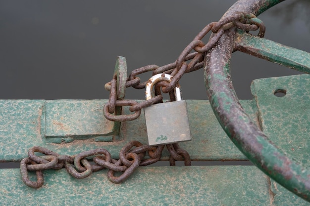 Un cadenas fermé sur une chaîne de fer bloque la roue de porte d'un fossé d'irrigation