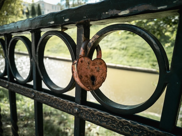 Un cadenas en forme de coeur sur un rail décoré d'antiquités en métal d'un pont au-dessus de la rivière