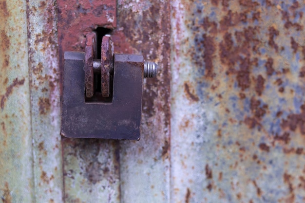 Le cadenas suspendu est verrouillé et suspendu à la vieille porte de garage rouillée de la cellule