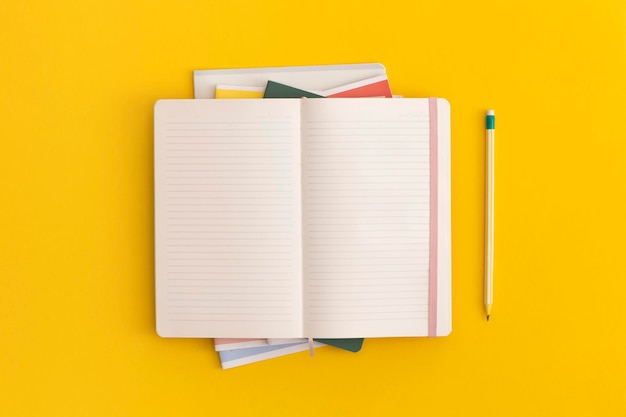 Cadern et crayon sur fond jaune vue supérieure à l'étage à l'arrière du concept de l'école