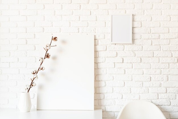 cadre d'affiche simulé avec une branche de coton sur un fond de mur de brique blanche