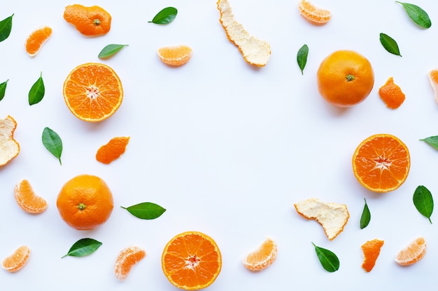 Cadre d&#39;agrumes orange frais avec des feuilles vertes sur blanc