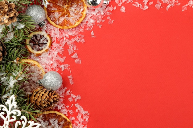 Cadre avec un arbre de Noël et des décorations colorées sur fond rouge clair