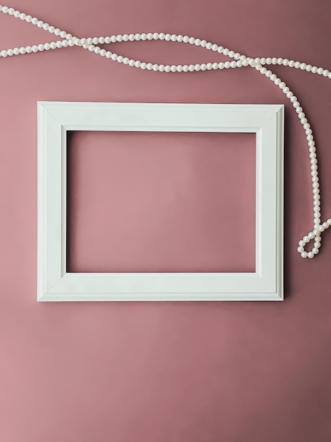 Cadre d'art horizontal et bijoux en perles sur fond rose blush comme impression d'œuvres d'art à plat ou album photo