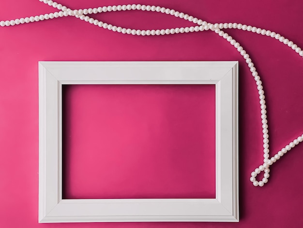 Cadre d'art horizontal blanc et bijoux en perles sur fond rose comme impression d'œuvres d'art à plat ou album photo
