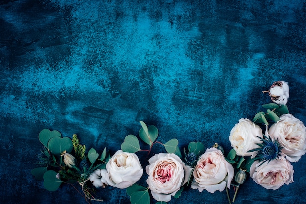 Cadre de belles fleurs avec des roses sur fond bleu