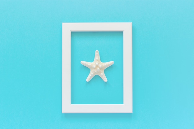 Cadre blanc avec étoile de mer sur fond bleu. Modèle de vue de dessus plat créatif pour carte postale, conception Espace de copie pour le texte