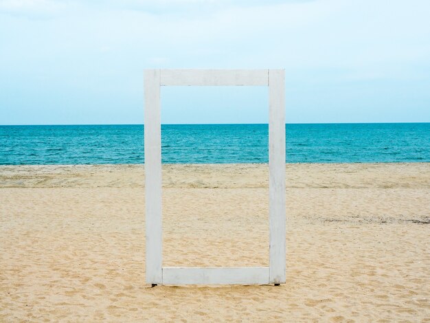 Un cadre en bois blanc blanc qui peut voir à travers le paysage marin, la plage, la mer et le ciel bleu