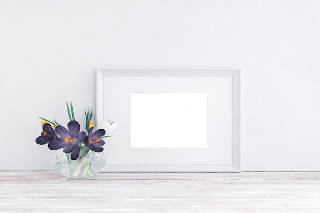 Photo cadre en bois blanc vide et fleurs dans un vase sur fond blanc avec espace de copie. maquette.