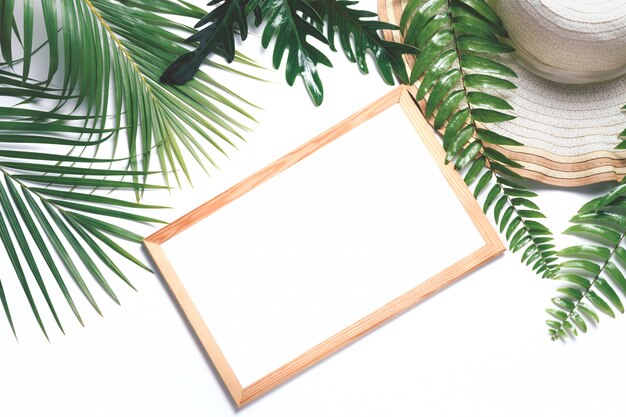 Cadre en bois blanc vierge avec feuille tropicale et grand chapeau isolé