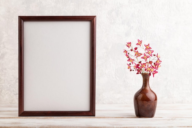 Photo cadre en bois avec des fleurs de barrenwort violettes dans un vase en céramique sur fond de béton gris vue latérale copie espace maquette