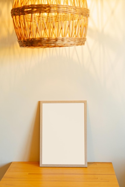 Un cadre en bois se dresse sur une table éclairée par une lampe jaune faite de matériaux naturels une place pour votre design et vos photos