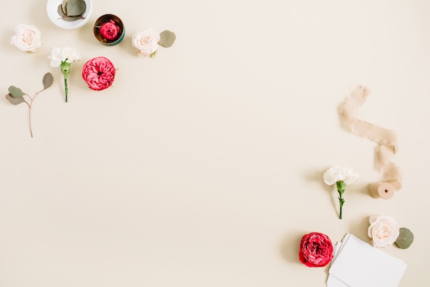 Cadre de bordure de fleurs en roses beiges et rouges et oeillet blanc sur beige pastel pâle