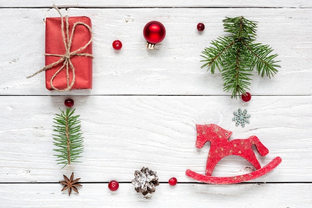 cadre en cadeau de Noël, pommes de pin, branches de sapin, boule rouge, baies et cheval jouet