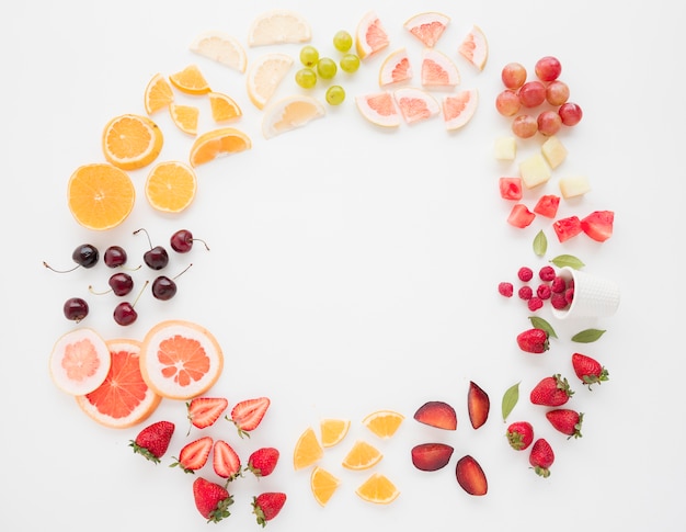 Cadre circulaire composé de nombreuses tranches de fruits sur fond blanc