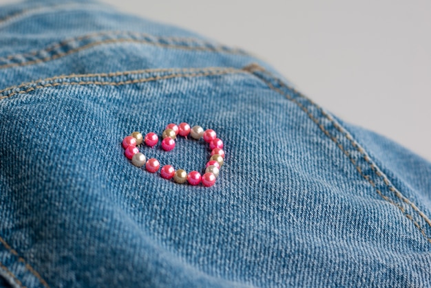 Cadre coeur fait d'aiguilles à coudre sur fond de jeans denim