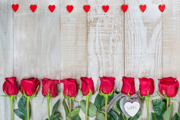 Cadre de coeurs et de roses sur une surface en bois clair.