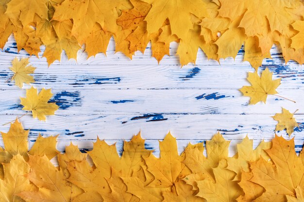 Cadre composé de feuilles d'automne jaunes et oranges sur fond en bois