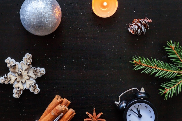 Cadre de composition de Noël nouvel an fait d'objets d'hiver horloge de bougie d'ornement de branche de sapin sur fond noir foncé. Espace de copie de vue de dessus à plat. Temps de décembre de Noël pour le concept de célébration