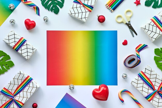 Cadre avec décor de Noël et cadeaux avec ruban arc-en-ciel aux couleurs du drapeau de la communauté LGBTQ