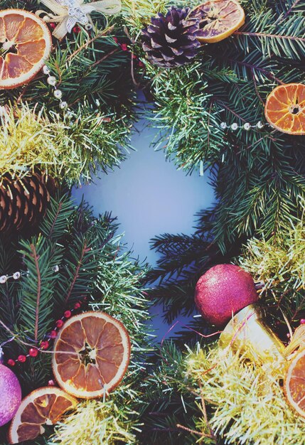 Cadre de décoration de Noël avec des tranches d'orange sèches et des boules colorées sur fond de neige blanche.