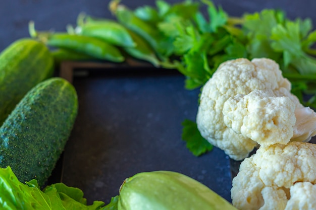 Cadre de différents légumes verts sains sur table sombre. Le concept d'une bonne nutrition et d'une alimentation saine. Nourriture biologique et végétarienne. Vue de dessus, mise à plat, espace de copie pour le texte.